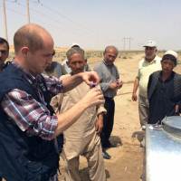 WHO technical staff testing chlorination of water with people affected by floods in Jawjzan province