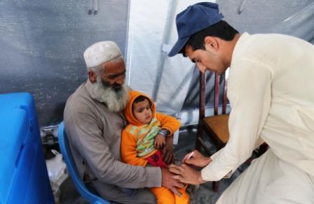 12._Razi_Khan_holds_his_daughter_Asma_as_she_gets_the_injectable_inactivated_polio_vaccine_IPV_at_the_IOM_transit_centre_near_the_Torkham_border