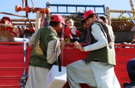 2._Polio_vaccinators_climb_up_a_truck_to_vaccinate_a_child_at_the_Torkham_border_in_Nangarhar_the_busiest_border_crossing_in_Afghanistan