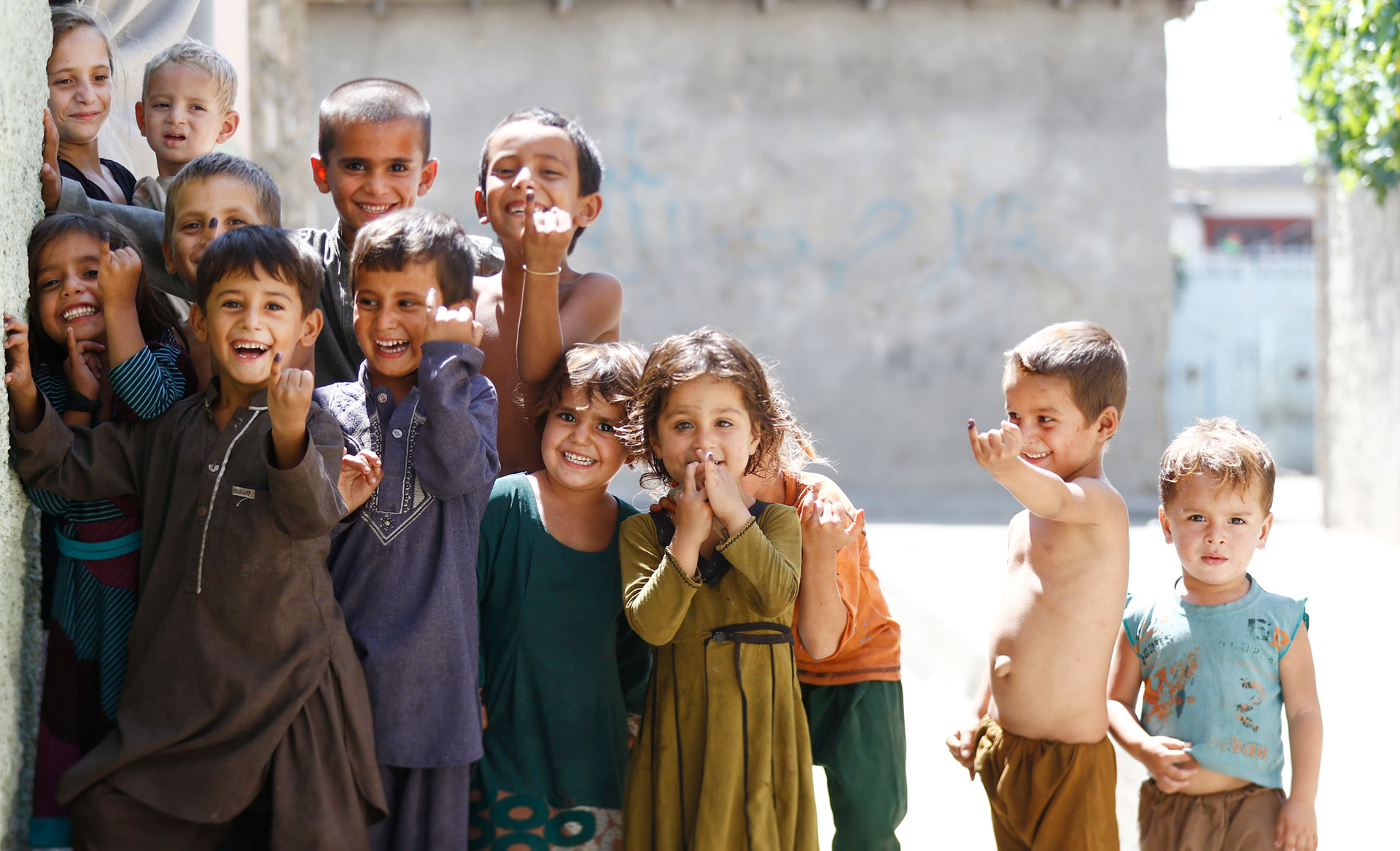 Afghani children proudly show inked fingers after receiving vital health services in their community