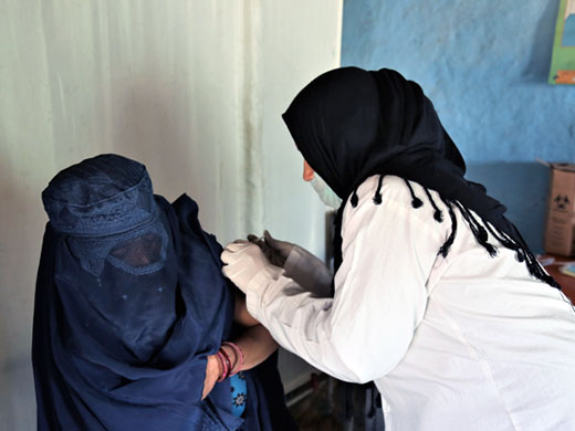 Credit: WHO Afghanistan/S.Ramo Zeeba administers a tetanus vaccine to Tahera at the Pul-e-Company mobile clinic in a camp for internally displaced persons. Tahera also brought her 18-month-old son, Ameer, to the clinic to get his essential vaccines. “Some of the camp residents refused vaccinations before. But now, after we have provided them with a lot of health education and information, they all accept vaccines and bring their children here to be vaccinated regularly. They all have vaccination cards,” Zeeba says.