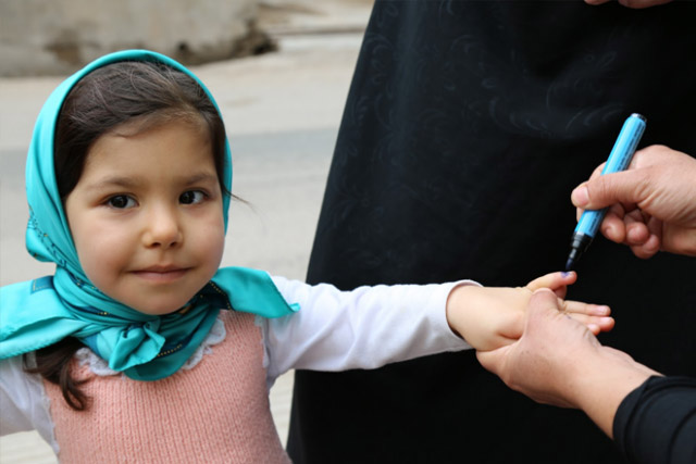 The children had their fingers marked with blue pen after being vaccinated. 4-year old Mahsa smiled as she received her finger mark.