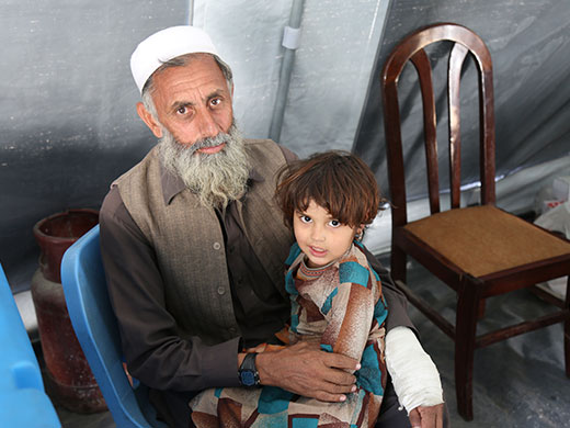 Photo credit: WHO Afghanistan/S.RamoWali Mohammad has lived in Pakistan for 25 years and is now returning because the authorities were harassing and threatening his family, pushing them to leave. Wali has seven daughters and five sons. “I broke my arm as I was rushing to pack all of our belongings to the truck,” he said, pointing to his white cast on his left arm while holding his 3-year-old-daughter Amina in the other at the IOM transit centre near the border in Nangargar. “My goal now is to find work and money to live,” Mohammad said, as he watched vaccinators administer measles and polio vaccines to Amina.