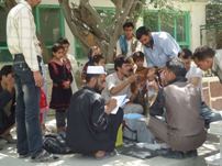 A young boy receives a measles and polio vaccine in a school yard, surrounded by other children, health workers and volunteers