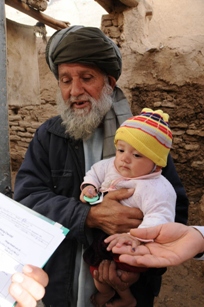 A man taking his daughter to receive a polio vaccination during the conducting of a national immunization day in Afghanistan