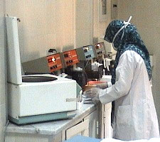 فنية المختبر ترتدي قناعاً وهي تتعامل مع العينة بعد استخدام جهاز الطرد المركزي 