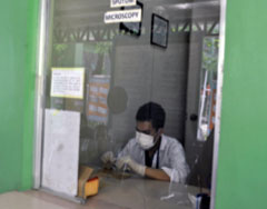 A laboratory technician at a TB clinic preparing sputum sample for microscopic examination