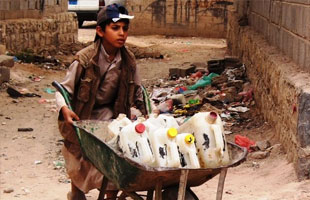 L’image nous montre un enfant transportant des jerricanes d’eau lors d’une flambée de choléra au Yémen