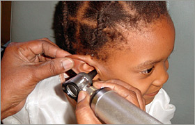 A doctor conducts an ear examination of a young girl