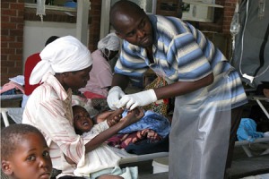 A photograph of a medical staff checking a young child during an outbreak of cholera