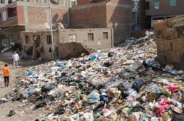 A photograph of a garbage dumping site located in the middle of households