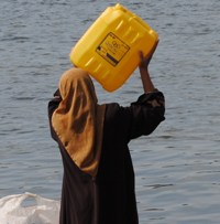 Photographie d'une femme portant un jerrycan d'eau