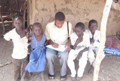 A surveillance officer sitting in the middle of a group of children and taking notes 
