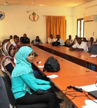 Groupe d'hommes et de femmes assis devant des tables disposées en U à l'occasion d'une formation