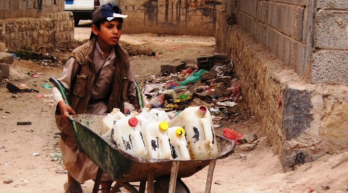 Boy transports bottles of water in a wheelbarrow