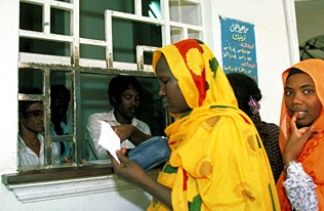 A woman holding a prescription while queuing up at a pharmacy counter