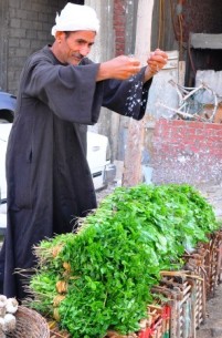 Street vendor splashing his green leafy vegetables with water