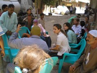 An informal meeting with community leaders takes place on a dusty unpaved street in Old Cairo, Egypt