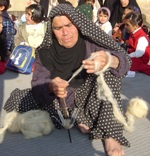 Elderly Iraninan woman sits spinning wool into yarn