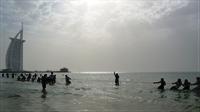 Men having a  tug of war contest in the sea close to the beach