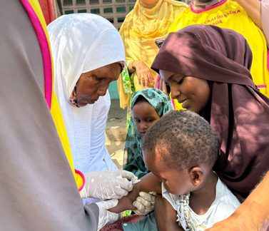 A health worker vaccinates a child during a community immunization drive.