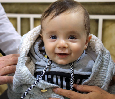 Four-month-old Walid Al-Ahmad smiles after receiving treatment at the Paediatric Clinic in Kurin Health Centre, Idlib. Photo credit: WHO
