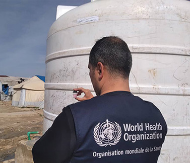 A WHO staff member collects a water sample for testing in Al-Hol camp to help ensure safe drinking water for displaced families