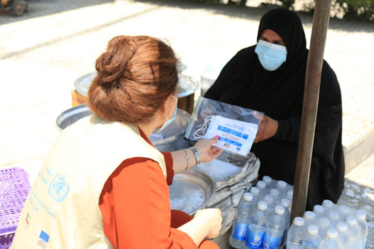 Hanan Amina recieves face masks for her family and self after engaging with volunteers conducting community education on COVID-19 in Al-Zaafraniya city