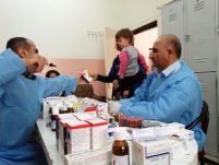 A mother receives medicine for her baby from mobile pharmacy team during a visit by the mobile clinic team to Sararm school in Duhok. 