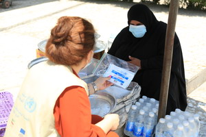 امرأة ترتدي قناعا ومعها مطهرا لليدين في حي الزعفرانية ببغداد