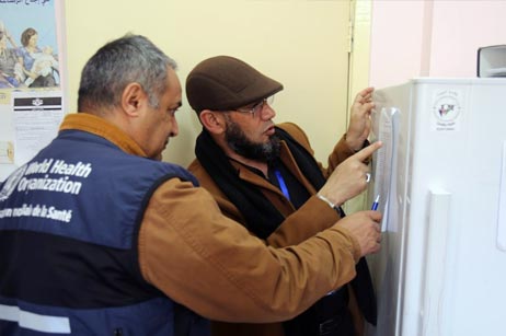 WHO technical officer and a Jerash Directorate of Health official check health centre refrigerator temperature records.
