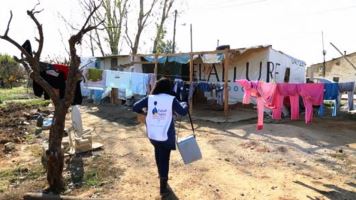 A health worker carrying the box of vaccines in an informal tented settlement 