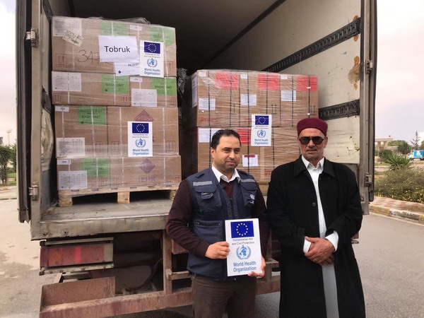 WHO staff member and local official of Tobruk stand in front of WHO truck of medical supplies
