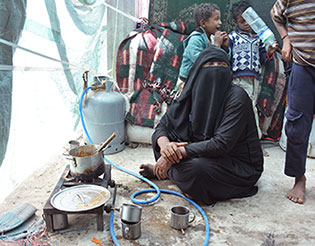 Aisha Ali, who fled to Ibb and is now living with 8 individuals in a tent cluttered by unclean kitchen utensils, worn clothes and empty tins