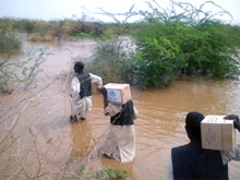 Le personnel de l’OMS et les volontaires transportent des boîtes de médicaments et des fournitures en traversant les zones inondées pour atteindre un centre de santé dans la localité d’Aroma, à Kassala, à l’est du Soudan.