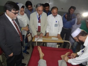 Officials watch a patient in a hospital bed receive a leishmaniasis treatment injection