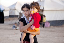 لاجئة سورية تحمل شقيقتها الصغرى