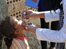 A health worker gives a child oral polio vaccine in Syria