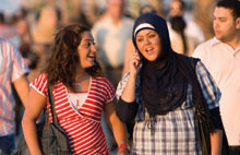 A large group of young people from the Region, with four young people in the foreground, walking down a boulevard in beautiful weather.