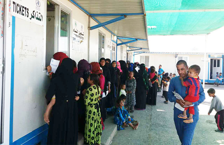 Women, men and children queue for health services in WHO’s only primary health care centre in Ba’ja town