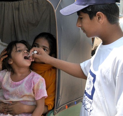 A polio worker administrating drops to a young girl in the polio campaign