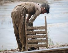 A man tries to salvage what remains of his house during the floods in 2010