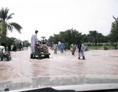 People navigate their way through flood water in Rajanpur, Punjab, as roads are turned into rivers.