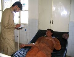The WHO pharmacist conducting an interview with a patient on a hospital bed