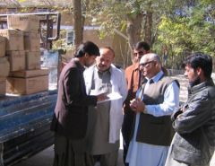 Health staff checking an inventory by a lorry stacked with boxes