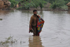 A man carries his belongings through knee-deep flood water in Sanghar, Sindh, in 2011