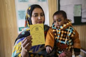 A mother holding a baby and a vaccine certificate