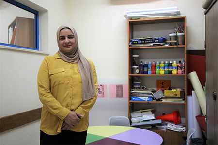 Aseel stands at the door of her office to welcome patients as they walk in. The entrance to her office is a colorful display of paints and art supplies, which she often uses to put her younger patients at ease.