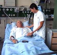 A male nurse tends to a patient in a hospital bed