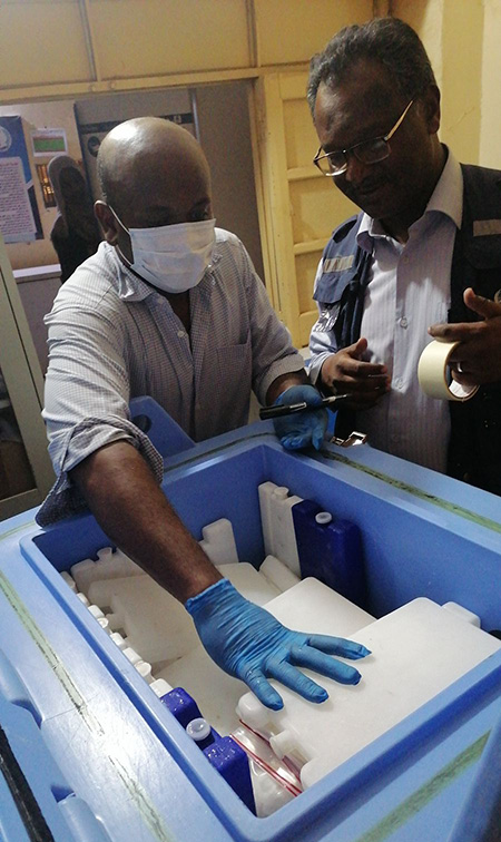 Dr Ameir Ibrahim, WHO Public Health Officer of Gezira State (right), and the State Cold Chain Officer of the Ministry of Health checking that stool samples are stored at optimum temperature. WHO/Sudan 